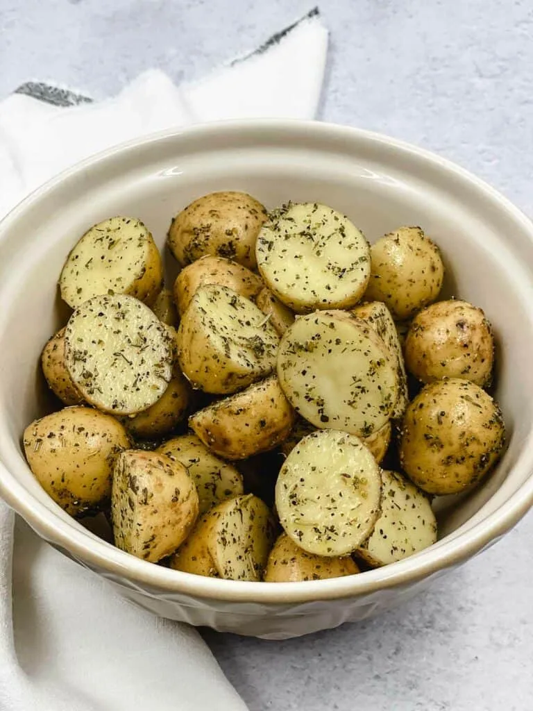seasoning air fryer potatoes in bowl